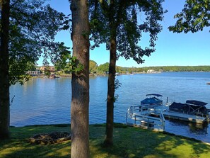 A lake with boats docked, surrounded by trees and buildings in the background.