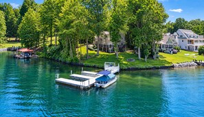 A river with a dock and a boat, surrounded by lush greenery and residential buildings.