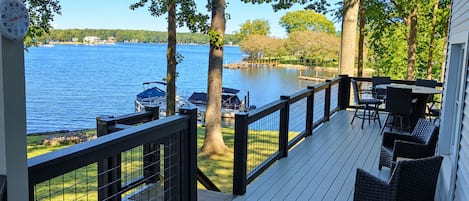 A deck with a railing, outdoor furniture, and a view of a lake.