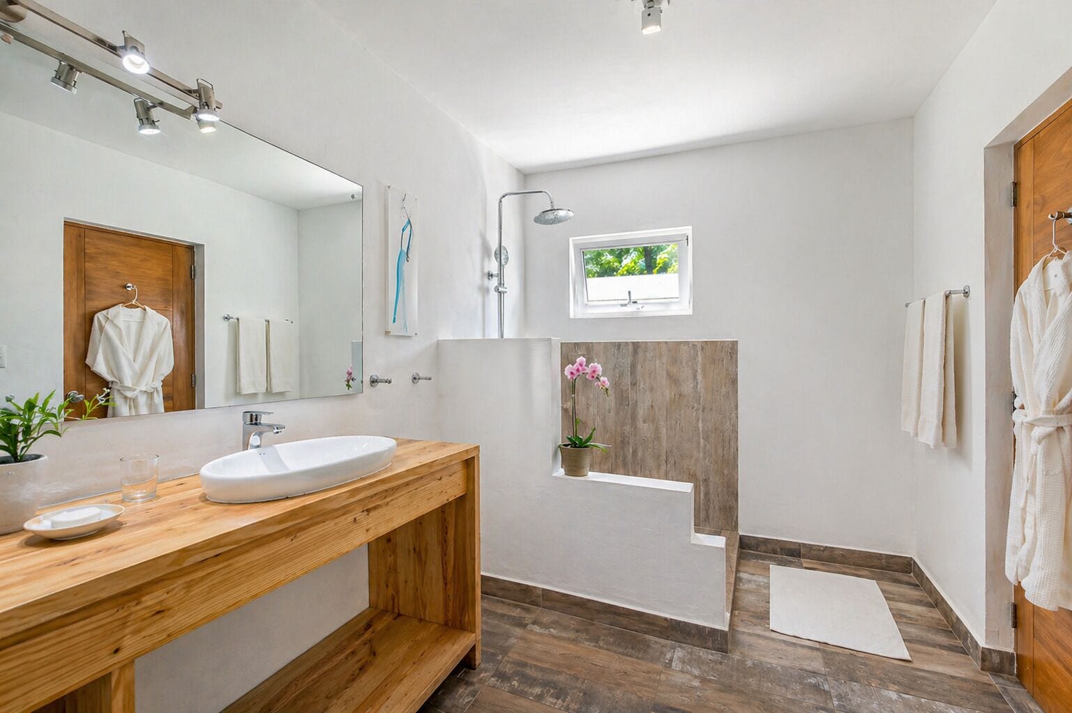 A modern bathroom with a wooden vanity, a large mirror, a shower, and a small window.