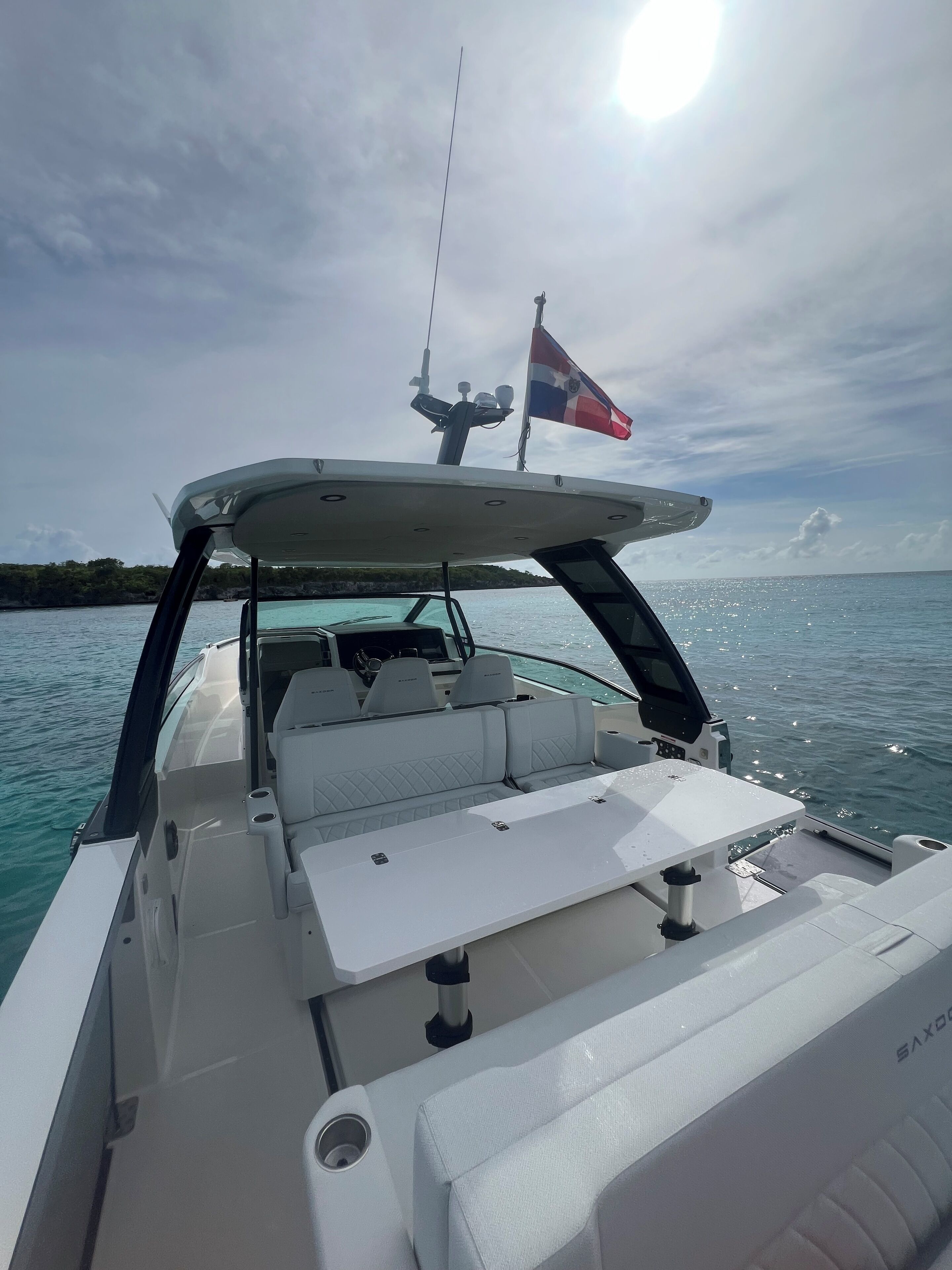 A boat's interior with a white cushioned seating area, a control panel, and a flag.
