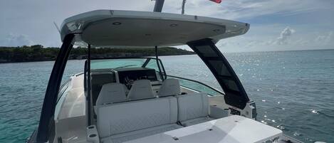 A boat's interior with a white cushioned seating area, a control panel, and a flag.