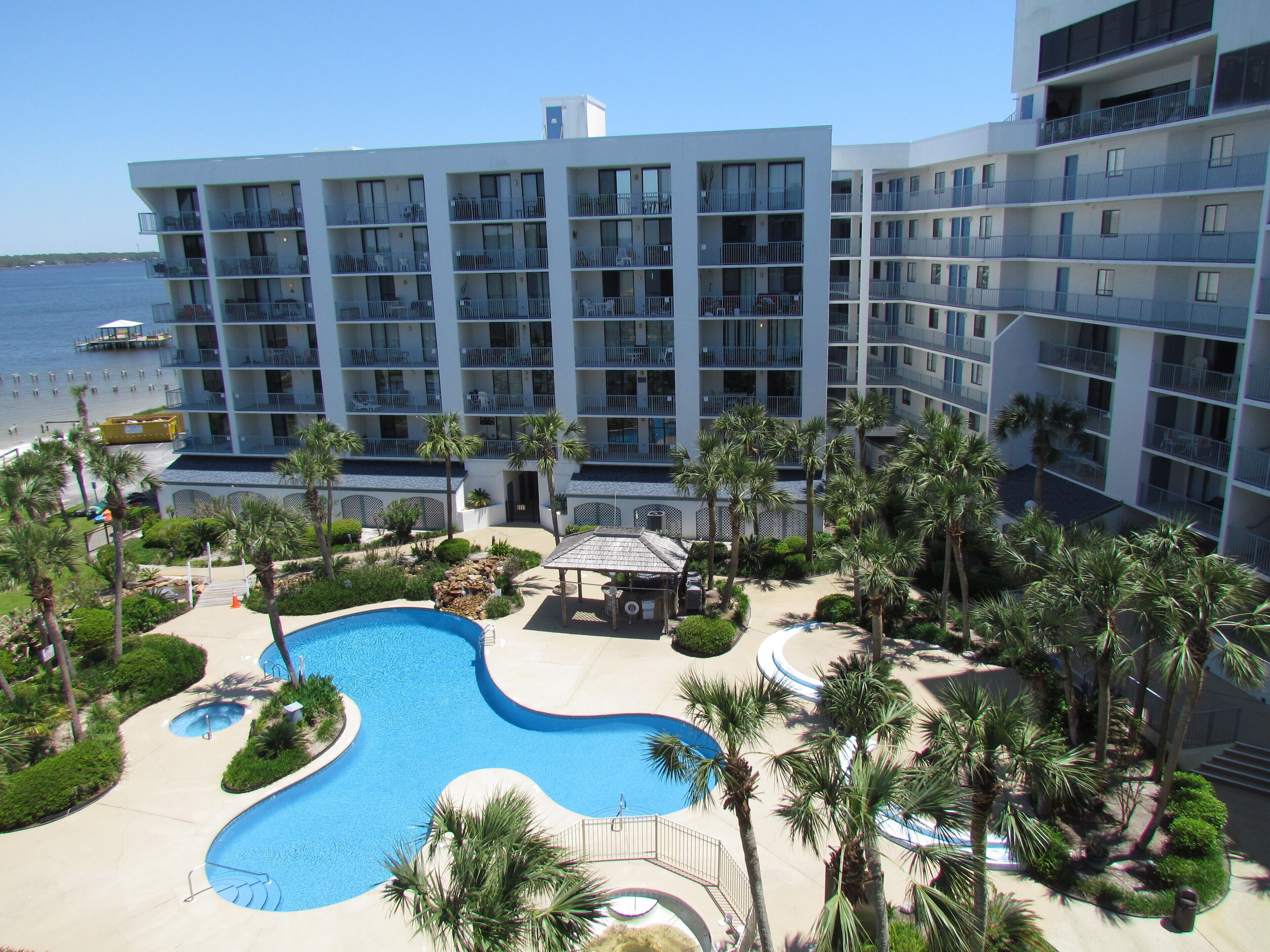 Un hôtel à plusieurs étages doté d’une piscine et de palmiers.