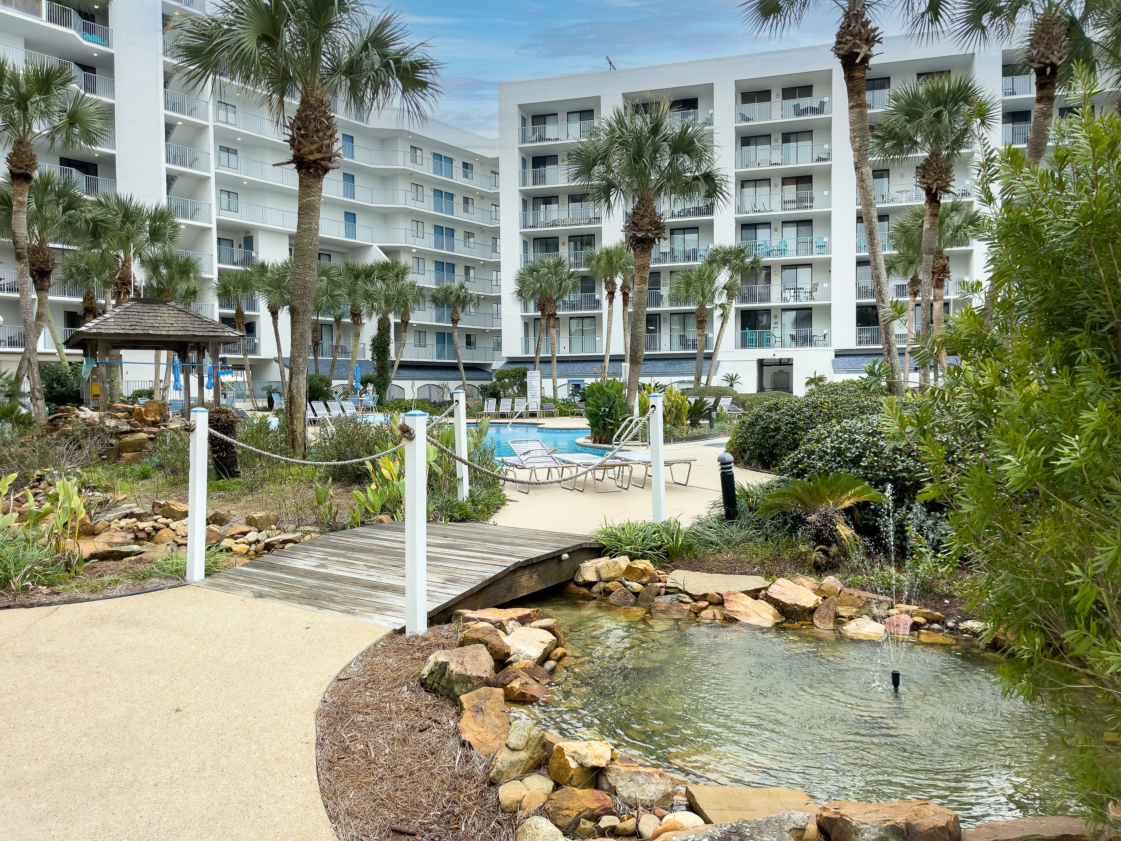 Ein Resort mit Pool, Liegestühlen und einem kleinen Teich, der von Steinen und Pflanzen umgeben ist.