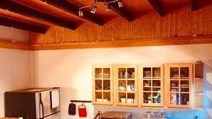 Une cuisine compacte avec des poutres en bois, un réfrigérateur, un four à micro-ondes, une cuisinière et des armoires en bois.