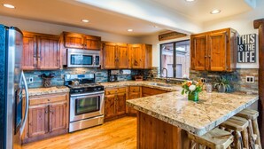 Una cocina moderna con armarios de madera, electrodomésticos de acero inoxidable y una encimera de granito.