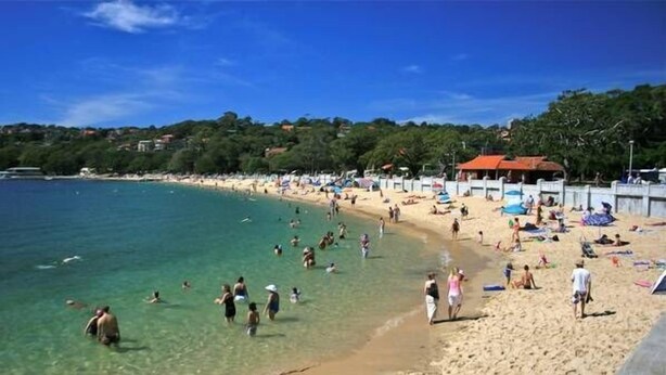 A beach with clear water, people swimming and sunbathing, and beach umbrellas. - Balmoral Escape - footsteps from beach (Mosman)