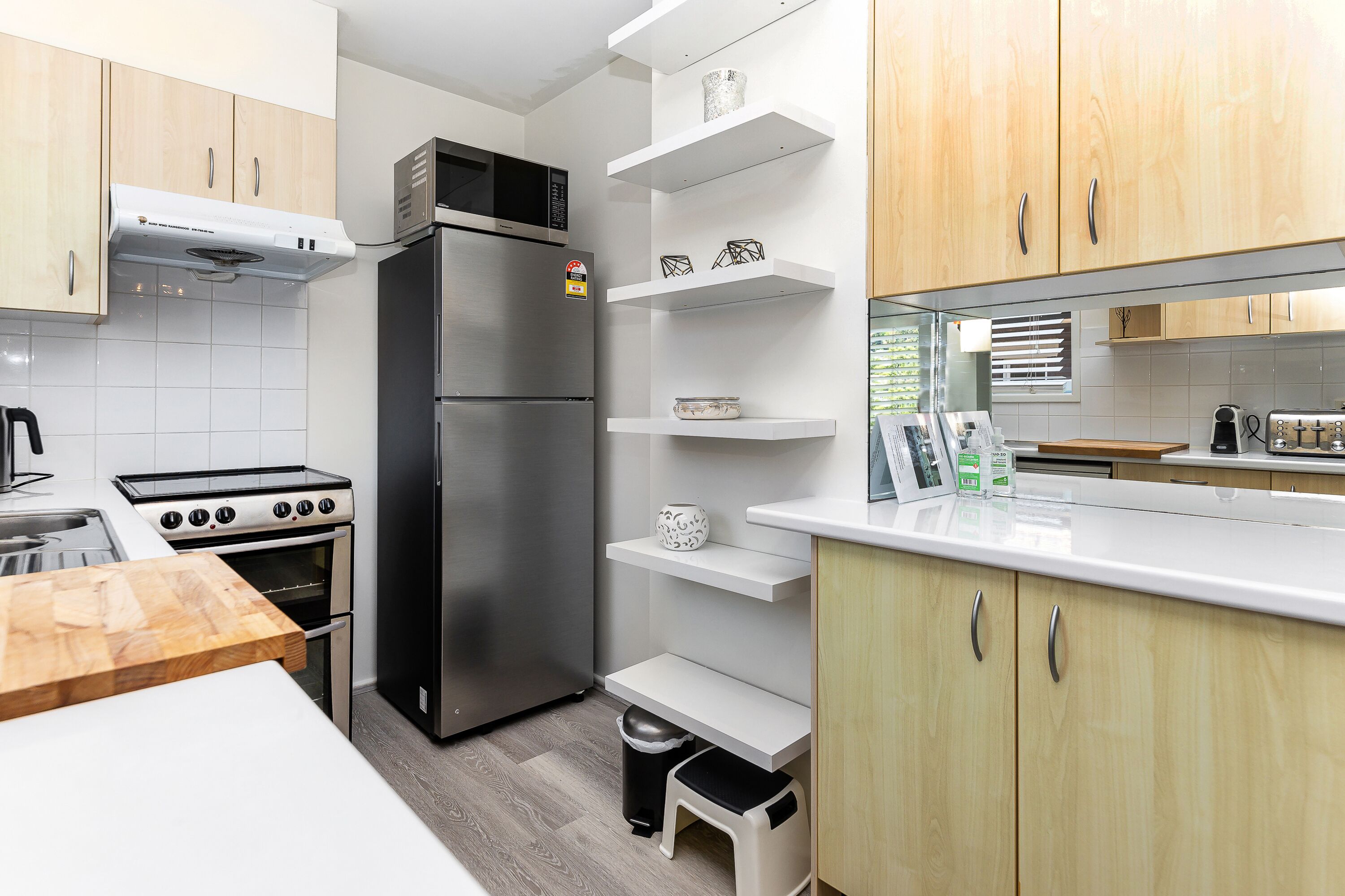 Eine moderne Küche mit Edelstahlgeräten, Holzschränken und weißen Arbeitsplatten.