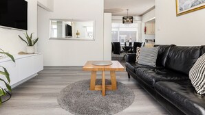 A modern living room with a black leather sofa, a wooden coffee table, and a grey rug. - Balmoral Escape - footsteps from beach (Mosman)
