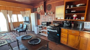 A cozy kitchen with wooden cabinets, a dining table with placemats, a refrigerator, a stove, and a coffee maker.
