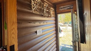 A wooden interior with a sliding door, a fire extinguisher, and a welcome mat.