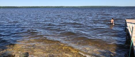 A rocky shoreline with clear water and a dock extending into the lake.