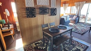 A dining area with a wooden table, chairs, and a patterned rug.