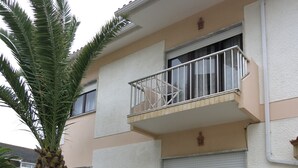 Un immeuble de deux étages doté de balcons, d’un palmier et de plantes en pot.