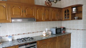 Une cuisine avec des meubles en bois, une cuisinière à gaz, un four, un four à micro-ondes et un dosseret carrelé.