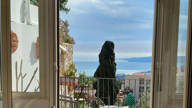 Un balcon avec vue sur la mer, une chaise et une table agrémentée d’objets décoratifs.