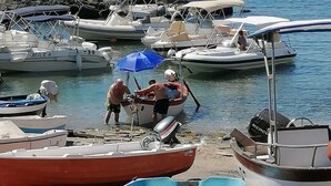 Un port de plaisance où sont amarrés plusieurs bateaux, une côte rocheuse et un ciel bleu dégagé.