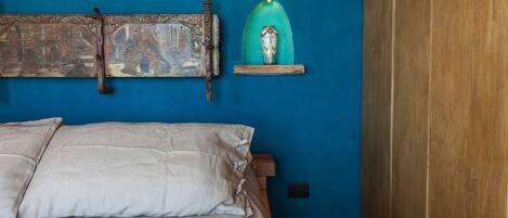 Een slaapkamer met een bed, een blauwe wand en een houten garderobe.