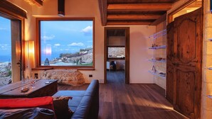 Ein gemütliches Zimmer mit großem Fenster und Blick auf eine reizvolle Landschaft, Holzbalkendecke und einer integrierten Ablage mit Dekoration.