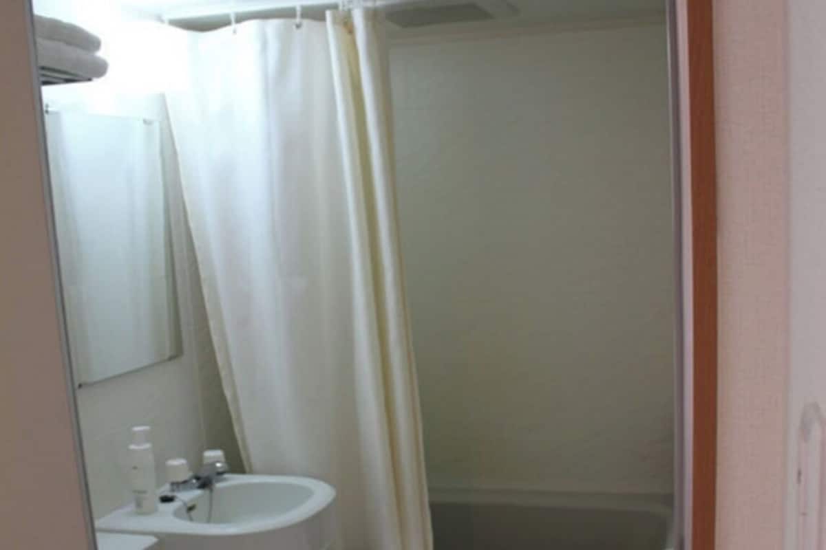 A small bathroom with a toilet, sink, and shower area.