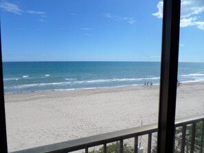 Ein Strand mit freiem Blick auf den Ozean und ein paar Personen, die am Ufer entlanggehen.