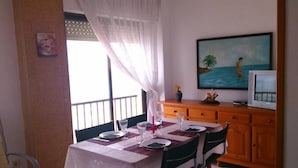 A dining area with a table set for two, a television, and a painting on the wall. - Apartment/ flat - DeniaResidential flat (Denia)