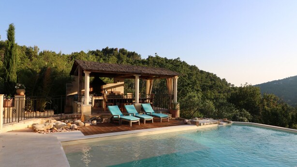 A pool area with lounge chairs, a pergola, and a view of a forested hillside. - Exceptional luxury house, poolhouse area and heated swimming pool (Seillans)