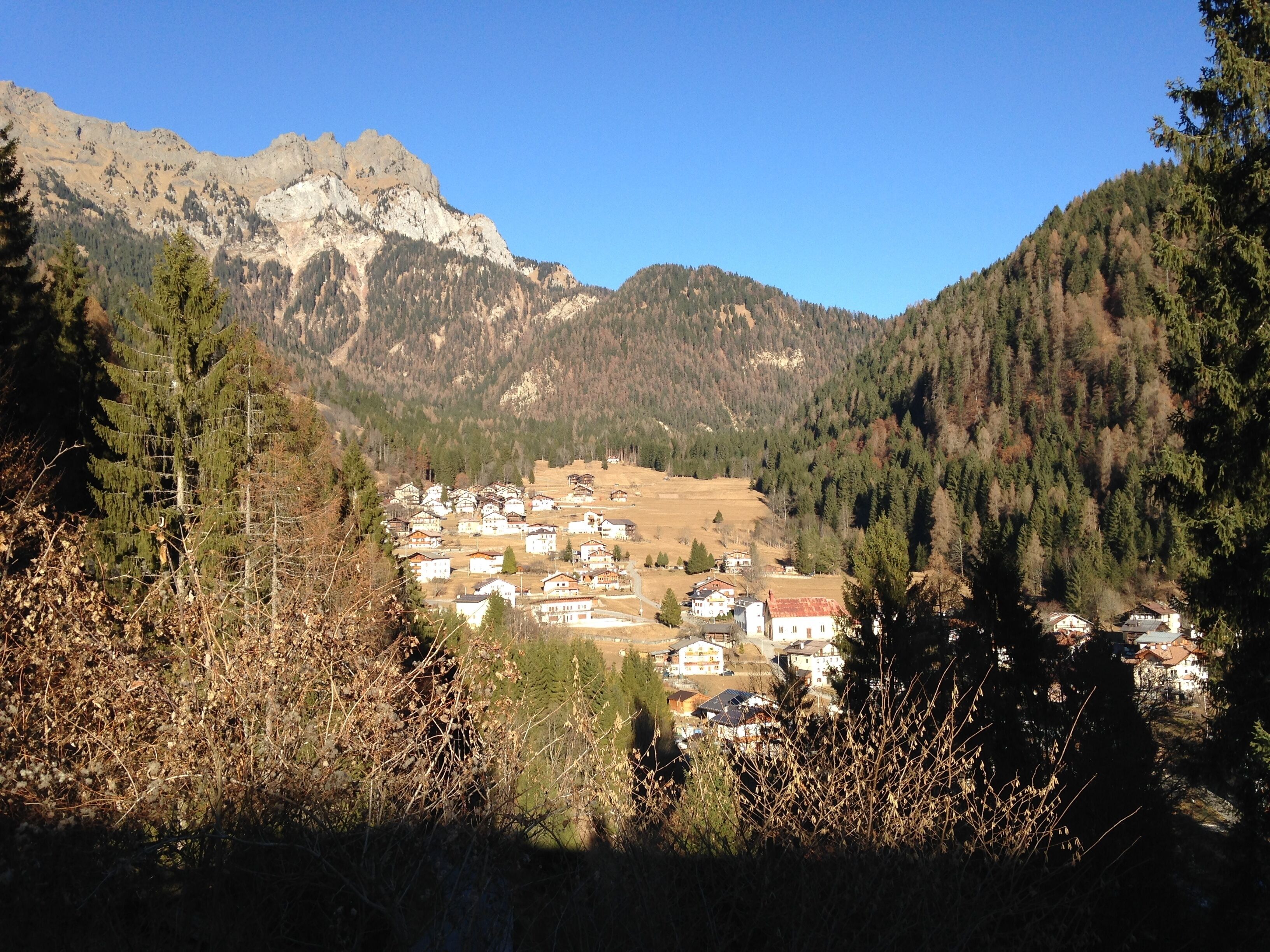 A mountain village with traditional houses, surrounded by dense forests and mountains.