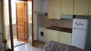 A compact kitchen with a washing machine, a refrigerator, and a sink. - apartment 300 meters from the sea (Follonica)