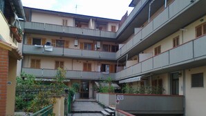 A multi-story residential building with balconies, a gated entrance, and a sign indicating a parking area. - apartment 300 meters from the sea (Follonica)