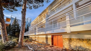 A modern building with a stone facade, a wooden door, and a balcony with metal railings. - Agi Marina 8 Apartamento for rent in Roses Girona. (Rosas / Roses)
