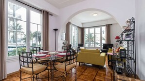 A dining area with a round table and chairs, a sofa, and a TV. - WATERFRONT PANORAMIC Seaview 2bd/2bath Apt on Promenade Des Anglais by Negresco  (Nice)