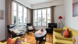 A modern living room with a sofa, armchairs, a coffee table, and a TV. - WATERFRONT PANORAMIC Seaview 2bd/2bath Apt on Promenade Des Anglais by Negresco  (Nice)