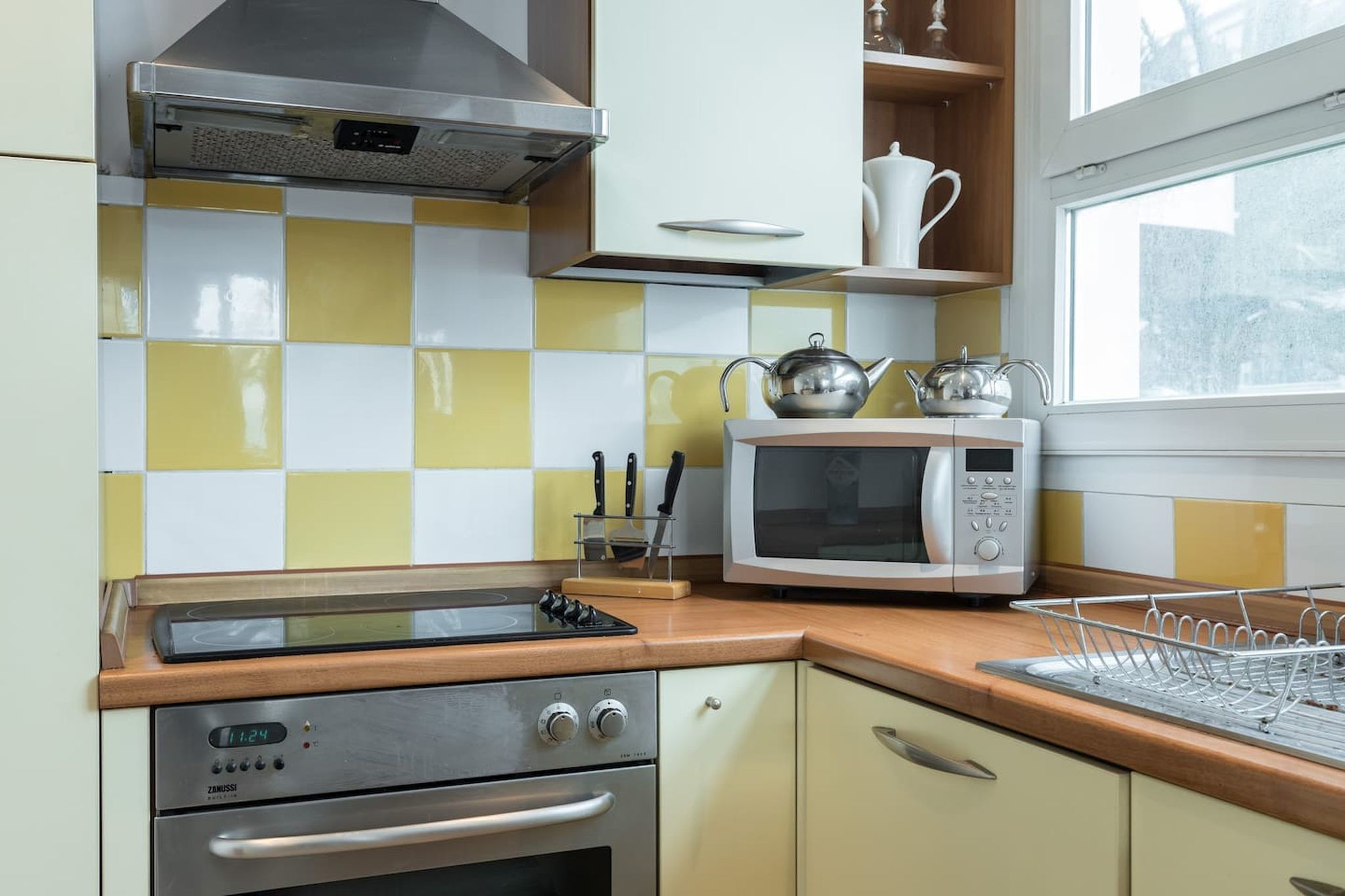 A kitchen with a stove, oven, microwave, and a window with a view.