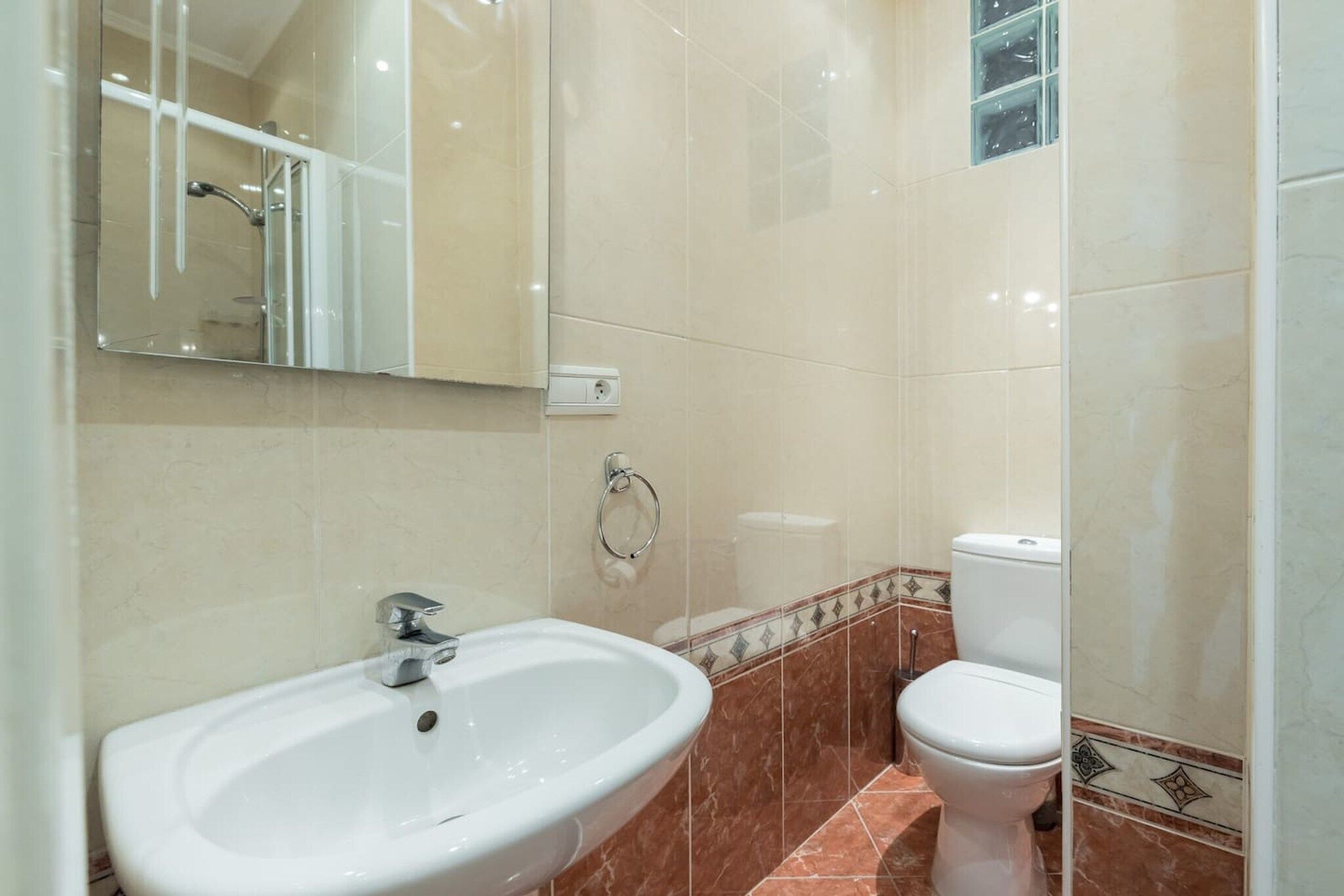A bathroom with a white sink, a mirror, a toilet, and a shower.
