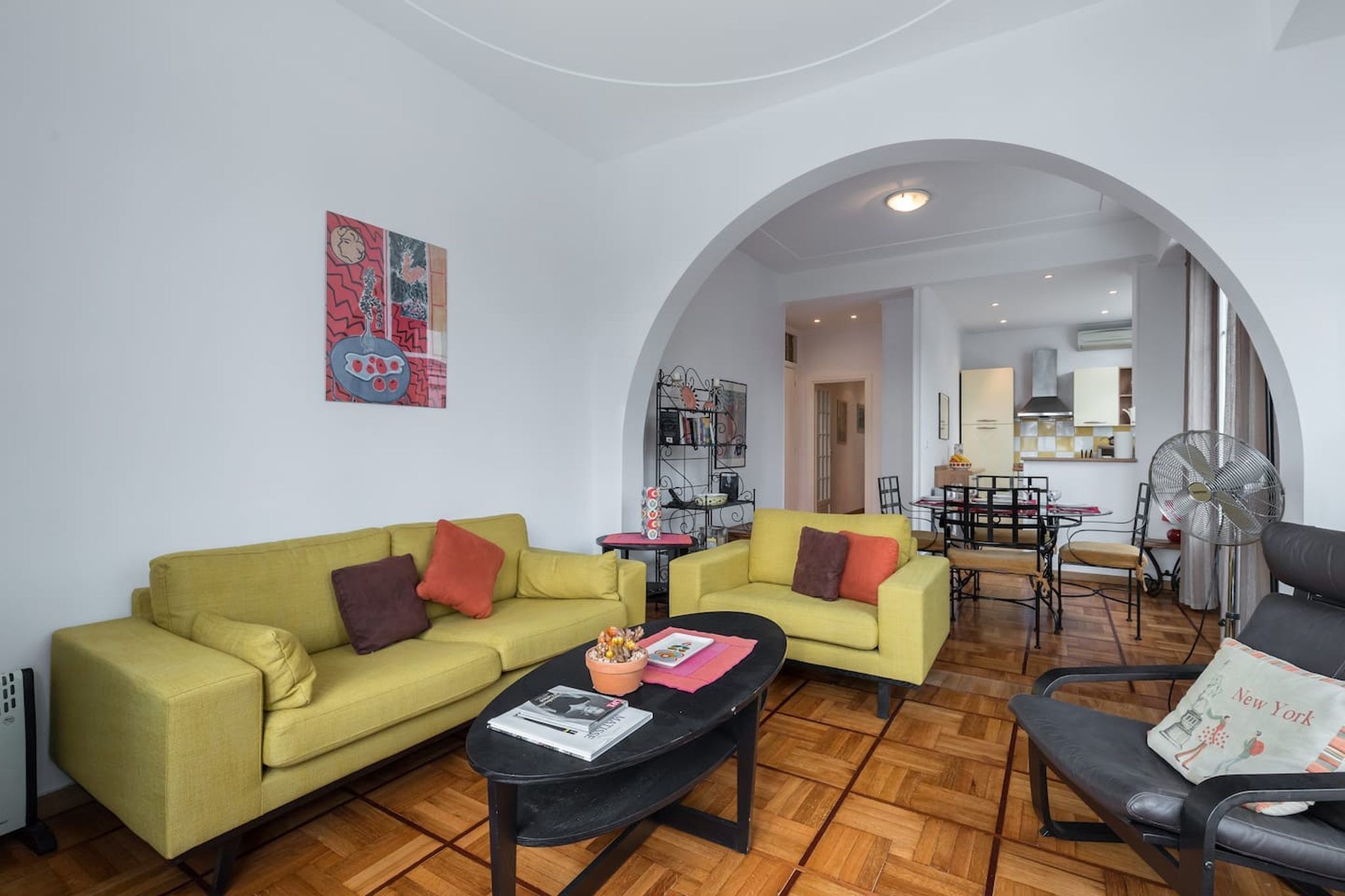 A living room with two sofas, a coffee table, and a dining area with a table and chairs.