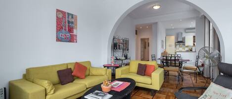 A living room with two sofas, a coffee table, and a dining area with a table and chairs.
