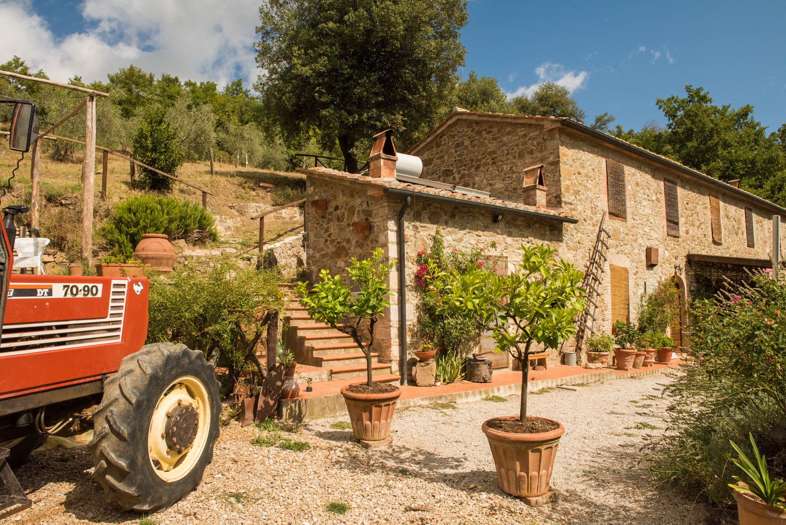 A stone building with a rustic exterior, surrounded by potted plants and a tractor.