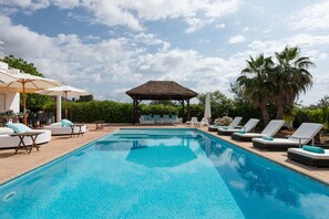 A swimming pool with lounge chairs and umbrellas, a covered seating area, and palm trees. - VILLA MARA - Private villa with pool, free fast WIFI & Alarm. Views to Playa den bossa beach. (Sant Josep de Sa Talaia / San Jose)