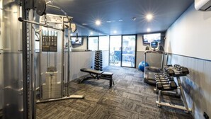 A gym with weight machines, a bench, dumbbells, and a treadmill. - The Sebel Brisbane Margate Beach (Margate)