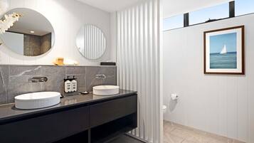 A modern bathroom with two sinks, a large mirror, and a framed picture on the wall.