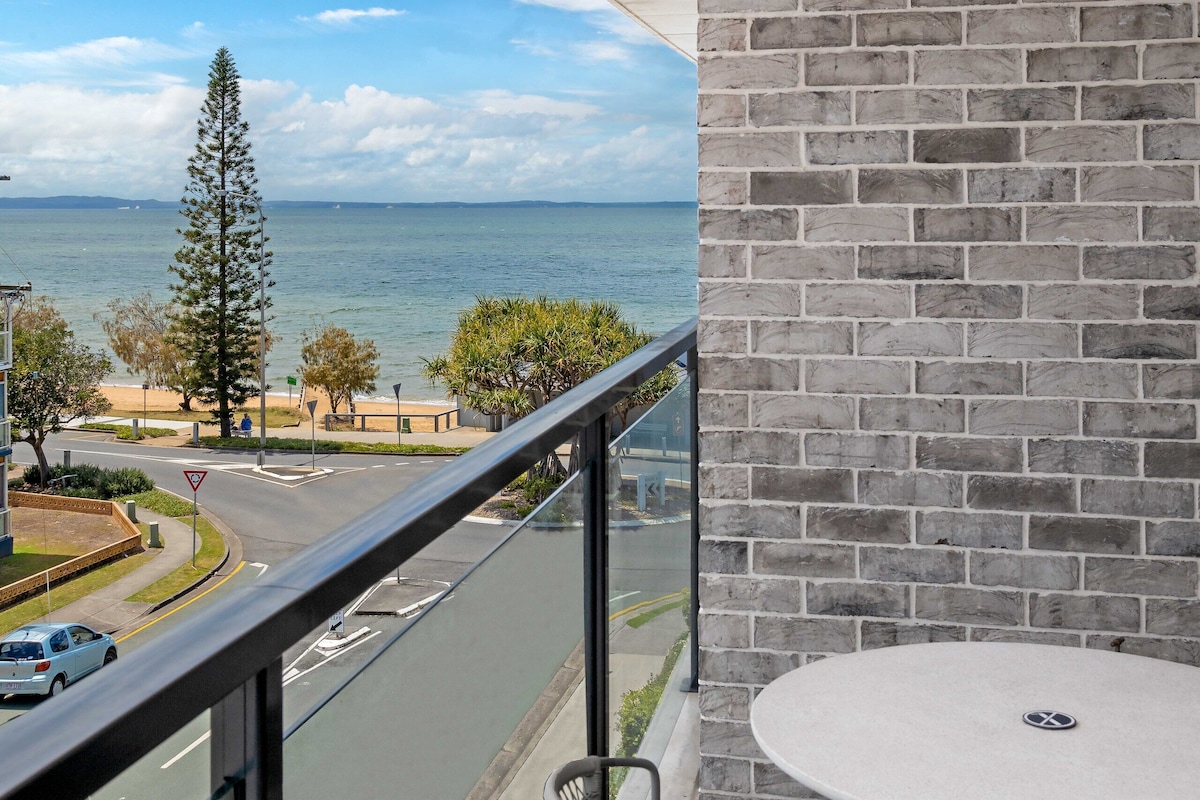 A balcony with a view of the sea, a round table, and a chair.