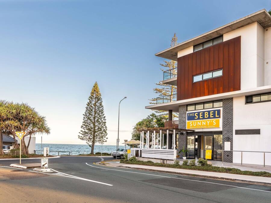 A modern building with a sign for 'The SeBel Sunnys' restaurant and bar.