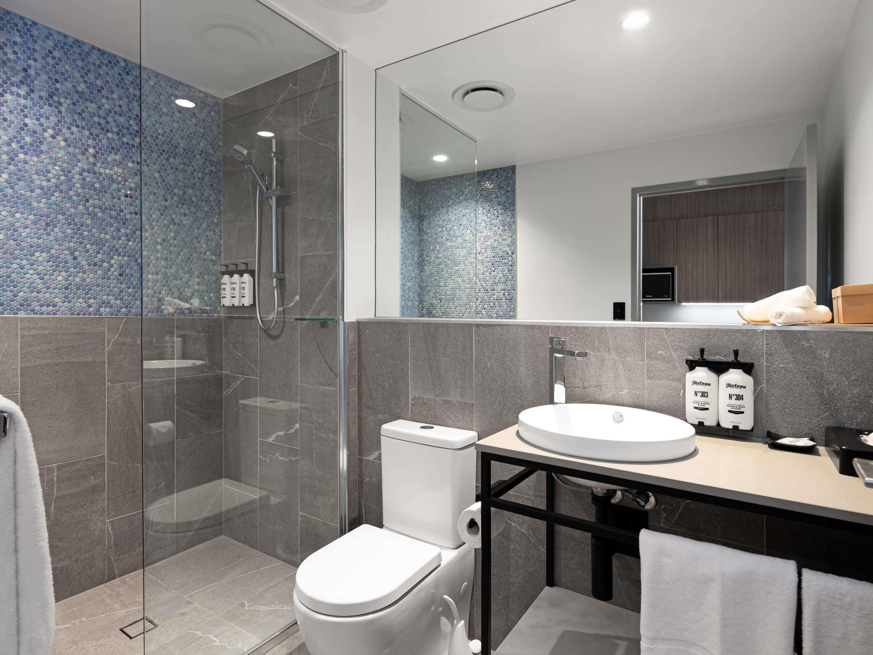 Un baño moderno con cabina de ducha de vidrio, inodoro, lavabo y espejo.