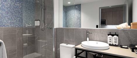 Un baño moderno con cabina de ducha de vidrio, inodoro, lavabo y espejo.