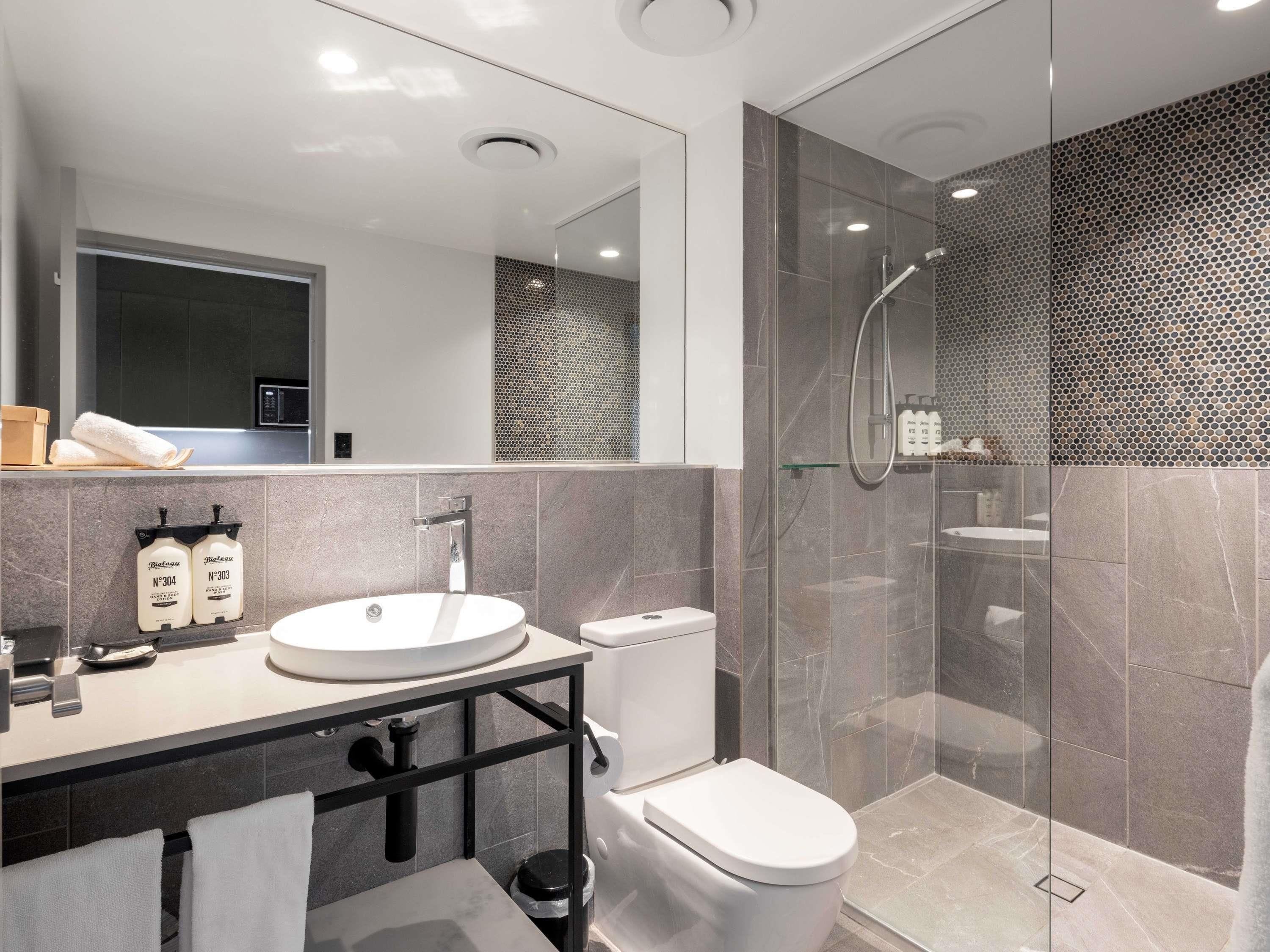 A modern bathroom with a glass-enclosed shower, a white sink, and a toilet.