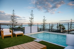 A rooftop pool area with a view of the ocean, surrounded by wooden furniture and a wooden deck. - The Sebel Brisbane Margate Beach (Margate)