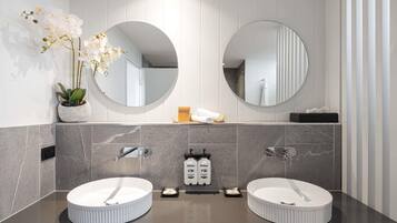 Un baño moderno con dos lavamanos, una orquídea en maceta y un espejo.