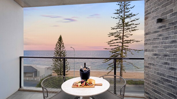 A balcony with a table set for a meal, overlooking a beach and the sea. - The Sebel Brisbane Margate Beach (Margate)