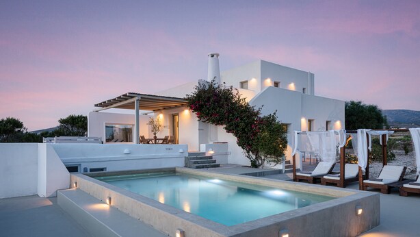 Un espace piscine moderne doté d’une piscine rectangulaire, de chaises longues et d’une pergola illuminée.